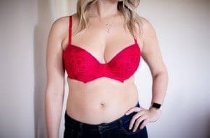 Blonde haired woman wears a red lce full coverage bra and some dark blue jeans