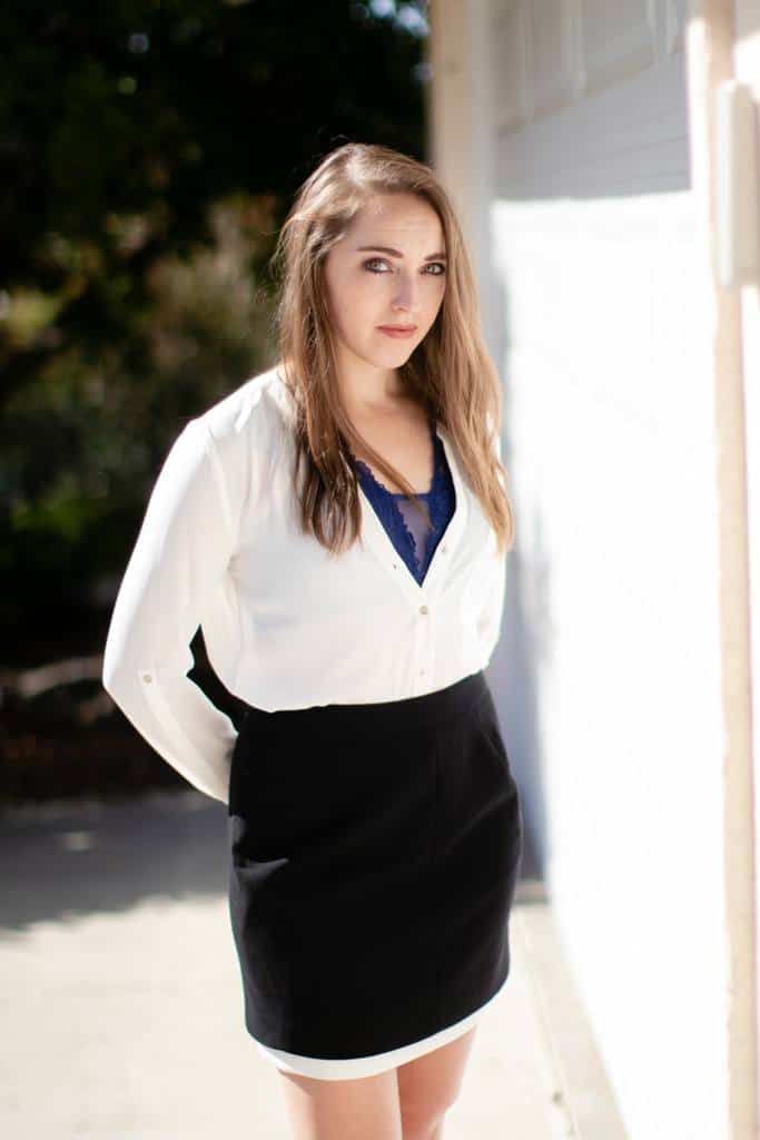 Woman wearing a blue mesh bralette with white top and black skirt