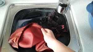 Woman holding a red bra to the sink for cleaning