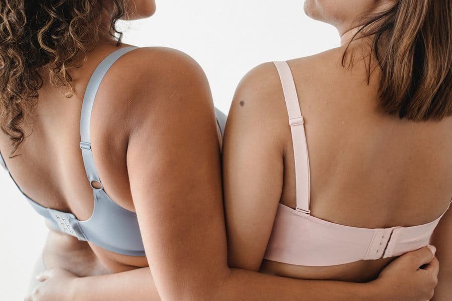 Girls both wearing bra that fits their sloping shoulders, while their hands are placed on each other's backs