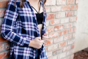 Woman wearing a plaid top over her black bralette