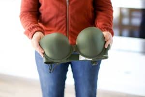 A person holding an olive green colored bra