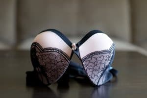 A white bra with a black lace design was placed on a black wooden table in the apartment