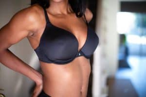 A woman wears a black padded push-up bra with a silver bead in the middle of the bra standing in the house