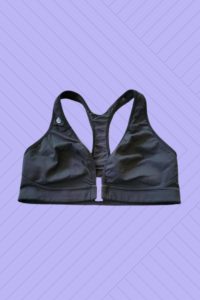 A black front clasp sports bra placed on a purple background