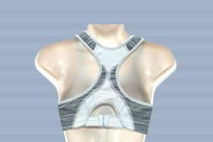 A back view of a gray and white sports bra placed on a white mannequin in a blue-striped background