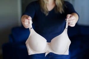 A woman wearing a blue blouse and blue jeans holds a white water bra near a blue couch in the living room