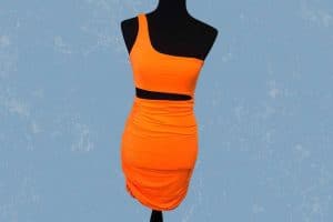 An orange one shoulder cut out bodycon dress placed on a black mannequin
