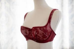 A red balconette bra with lace and an underwire placed on a white mannequin