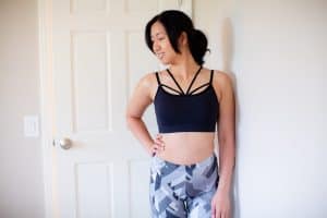 A woman in a dark blue racerback sports bra wearing gray leggings