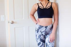 A woman in a dark blue racerback sports bra wearing blue and gray leggings