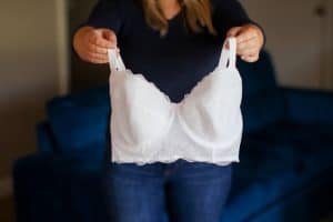 A person holding a white longline underwired bra with thick straps