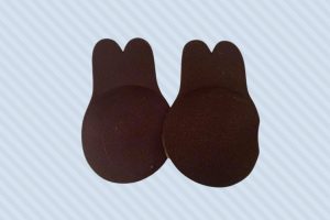 Brown adhesive silicone nipple cover placed on a blue background