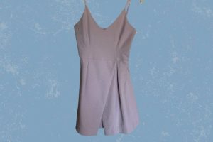 A gray spaghetti strap bodycon dress with a front slit placed on a blue background