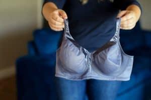 A dark blue wireless bra with a wide band and straps held by a woman