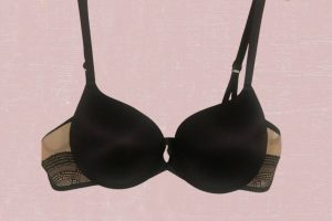 A black push-up bra with underwire and adjustable straps placed on a pink background