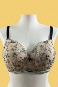 A cream full-coverage underwire bra with a floral lace design and black adjustable straps placed on a white mannequin