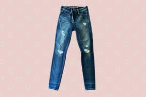 High-waisted straight cut tattered denim jeans placed on a pink background