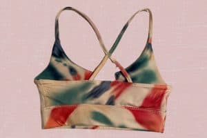 A back view of tie dye sports bra placed on a pink background