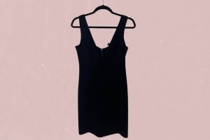 A black sleeveless bodycon dress hangs on a black hanger placed on a pink background