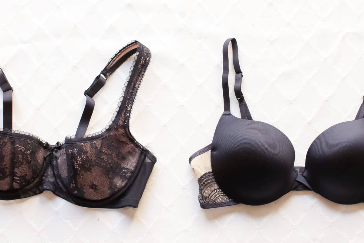 A black lace bra beside a full-coverage bra on a white surface