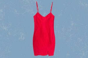 A pink spaghetti strap bodycon dress with a little slit placed on a blue background