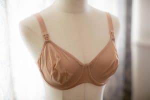 A nursing bra brown in color with front clips placed on a white mannequin