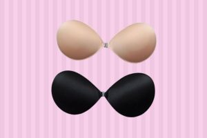 Two sticky bras in cream and black color with clasps placed on a pink background