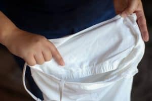 A white tank top with a built-in bra holds by a person in blue t-shirt