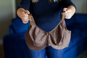 A woman holds a brown seamless bra with adjustable straps and ribbon at the center