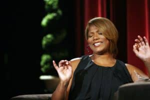 Queen Latifah wearing a black round neck and sleeveless top during a talk show appearance