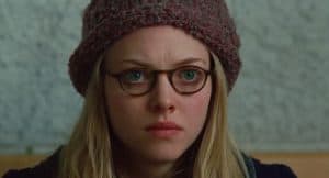 Amanda Seyfried with long-blond hair is wearing a bonnet and brown glasses