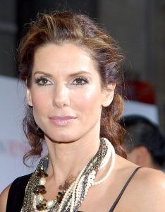 Sandra Bullock with brown hair wearing a black gown and Lanvin necklaces at a movie premiere