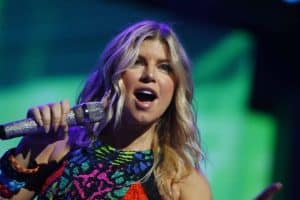Fergie wearing a multi colored halter top while holding a mic during a stage performance