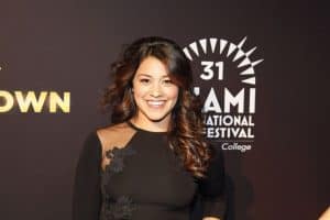 Gina Rodriguez wearing a black dress with a sheer lace on one shoulder