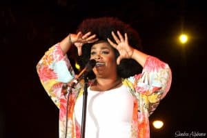 Jill Scott wearing a floral open kimono and a white shirt during a stage performance
