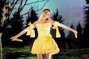 Madison Beer wearing a short yellow dress with big yellow ribbons on her arms