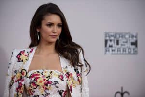 Nina Dobrev wearing a white dress and cape with flower details