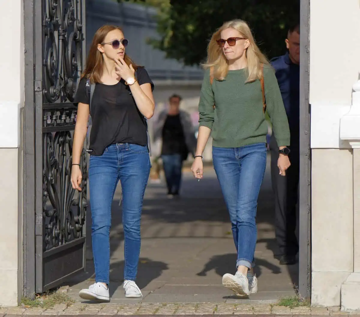 Two women walking wearing jeans and white shoes