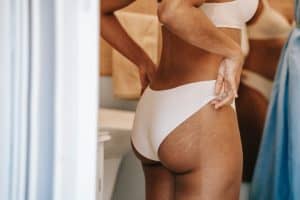 A woman facing backwards wearing white panty holding it side by side