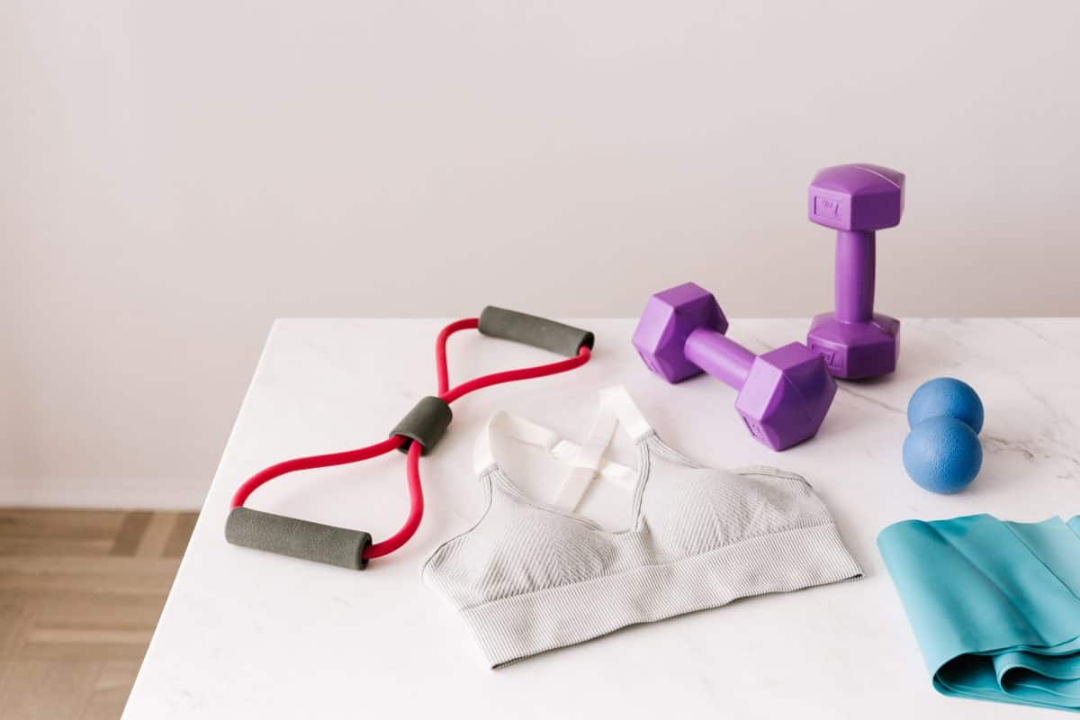 A sports bra with some workout tools beside it placed on a white table
