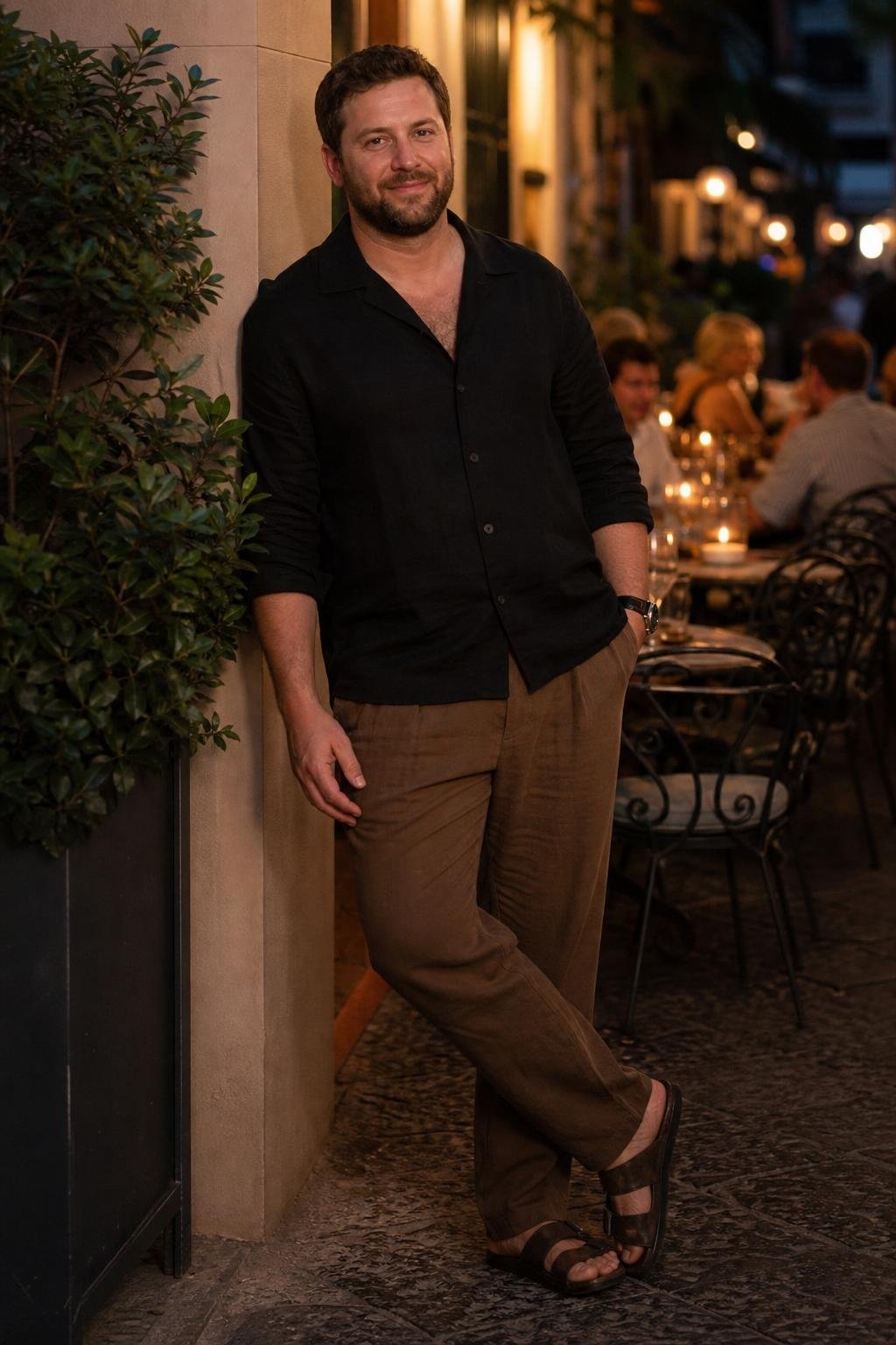 Black linen shirt, tobacco relaxed trousers, dark leather sandals, city evening restaurant patio (option 2)
