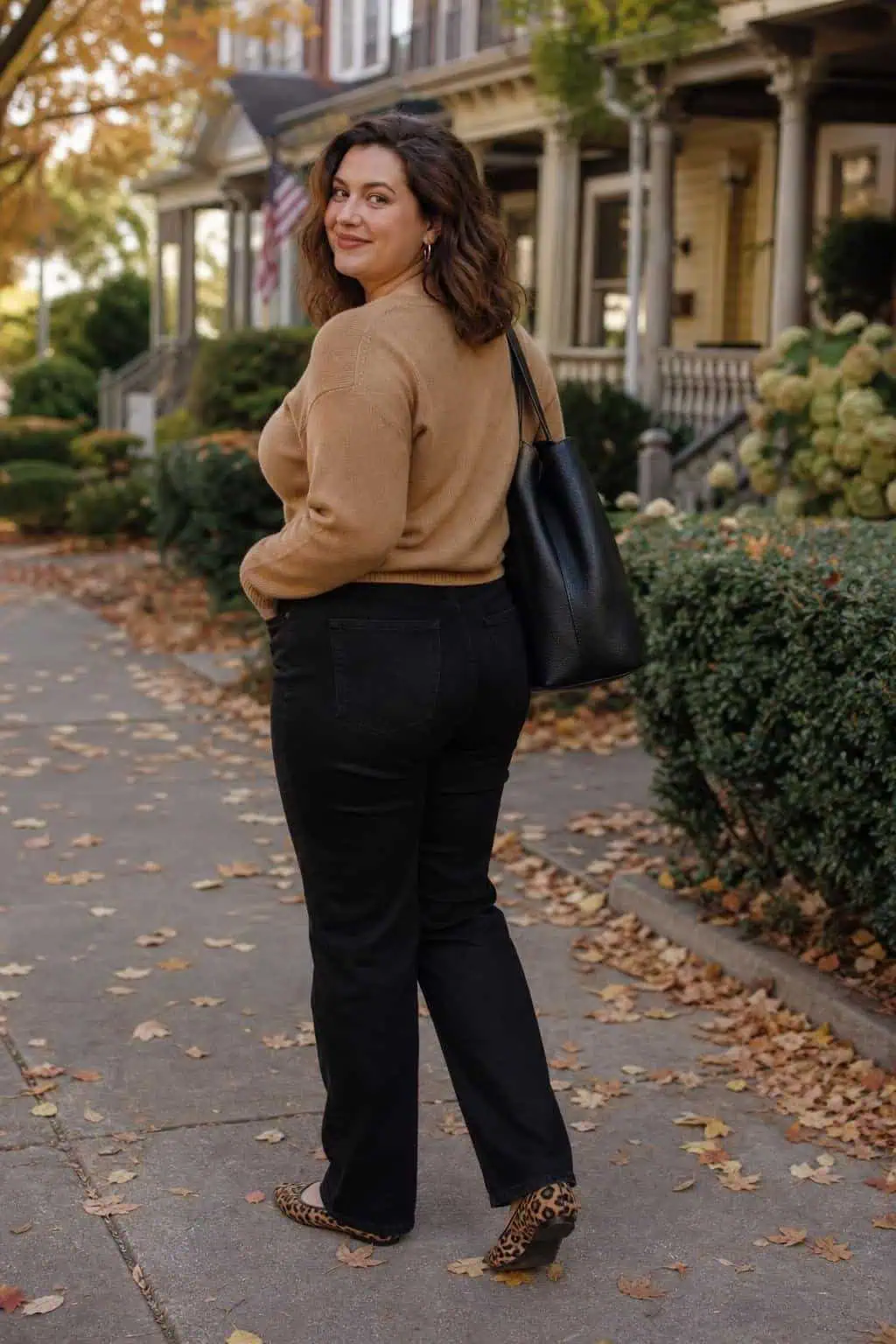 Camel crewneck sweater, black straight jeans, leopard flats, black tote on a leafy residential street (option 2)