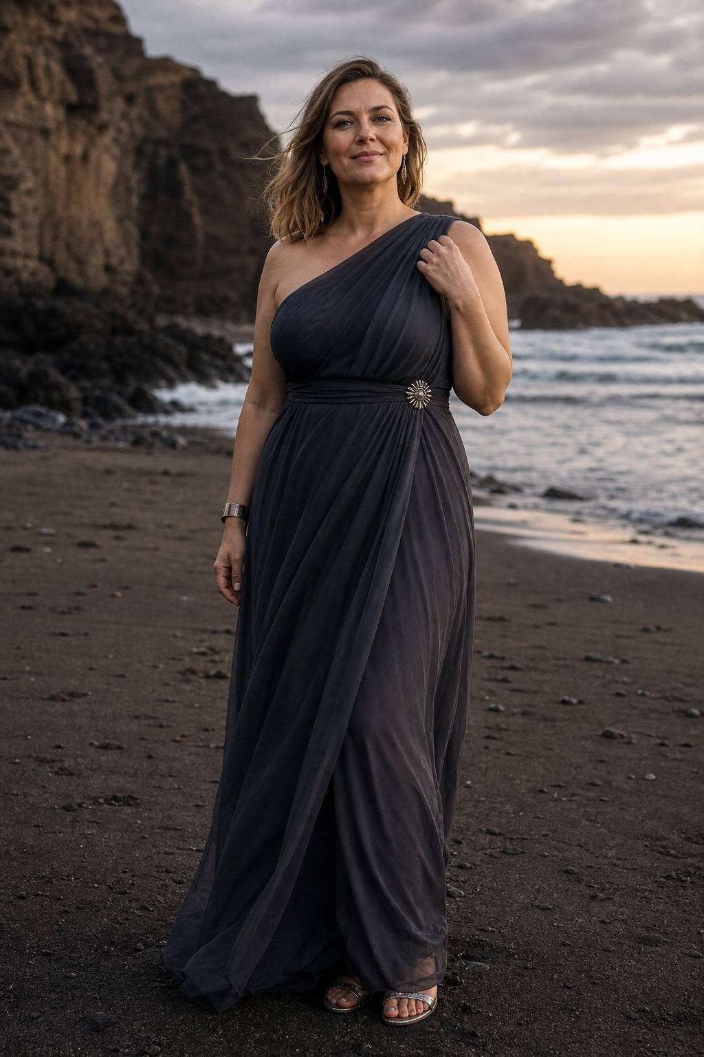 Charcoal Grecian maxi dress with pewter sandals on a dramatic rocky beach at dusk (option 1)