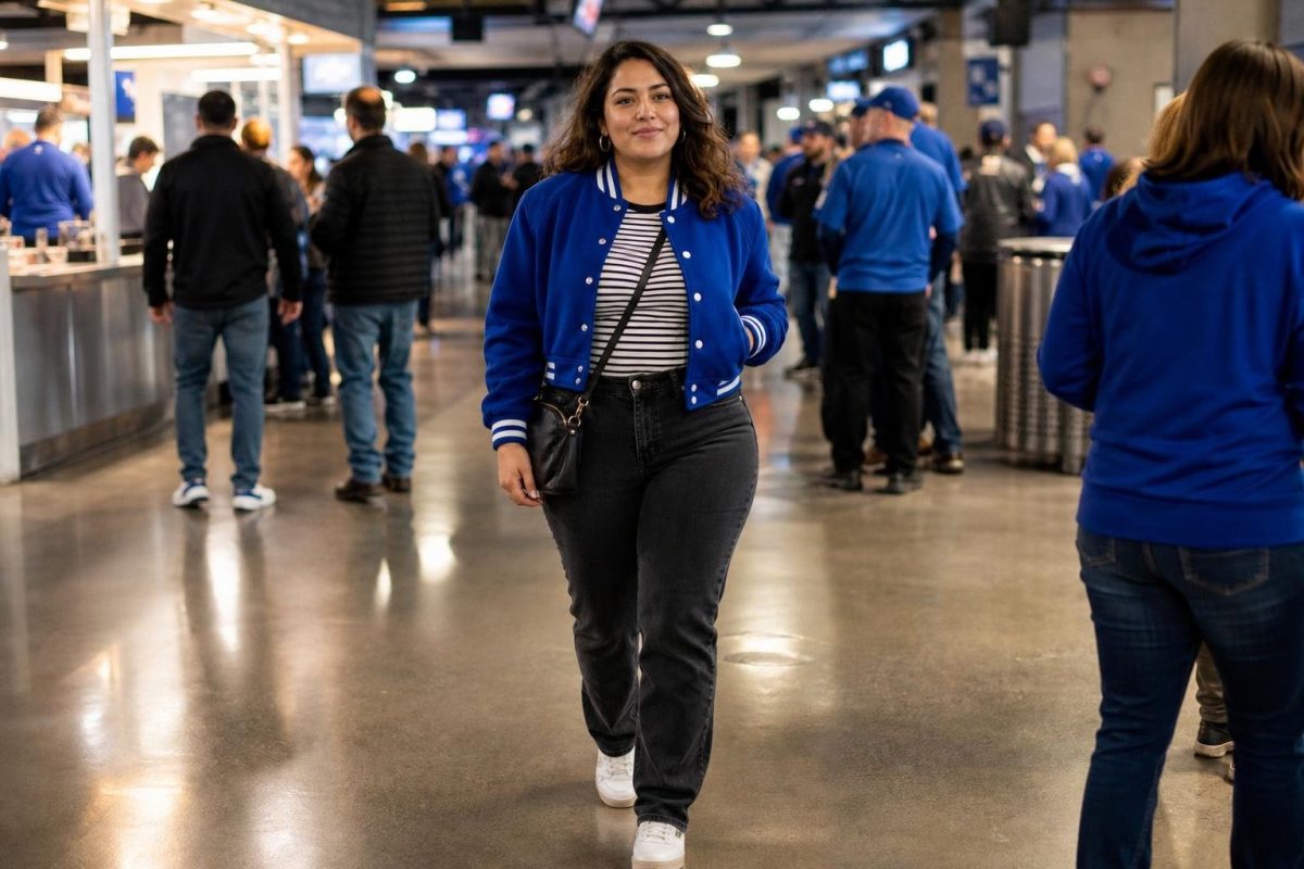 Cobalt varsity jacket, striped tee, charcoal jeans, clean sneakers, lively stadium concourse before kickoff (option 1)