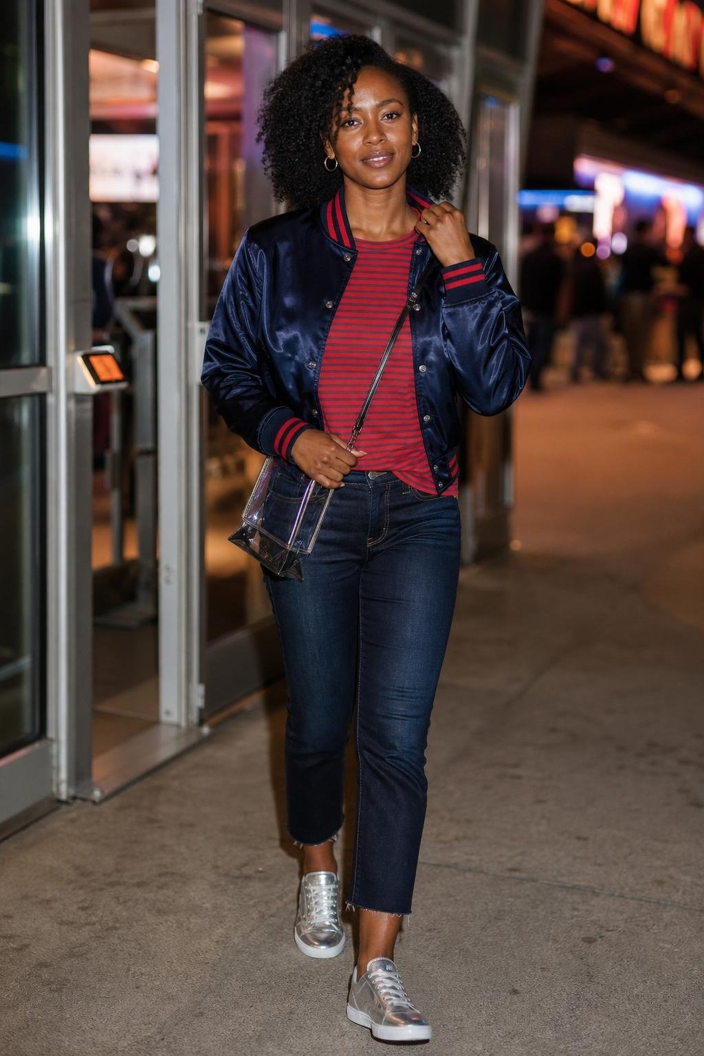 Navy satin bomber, red striped tee, cropped jeans, silver sneakers, evening arena entrance scene (option 1)
