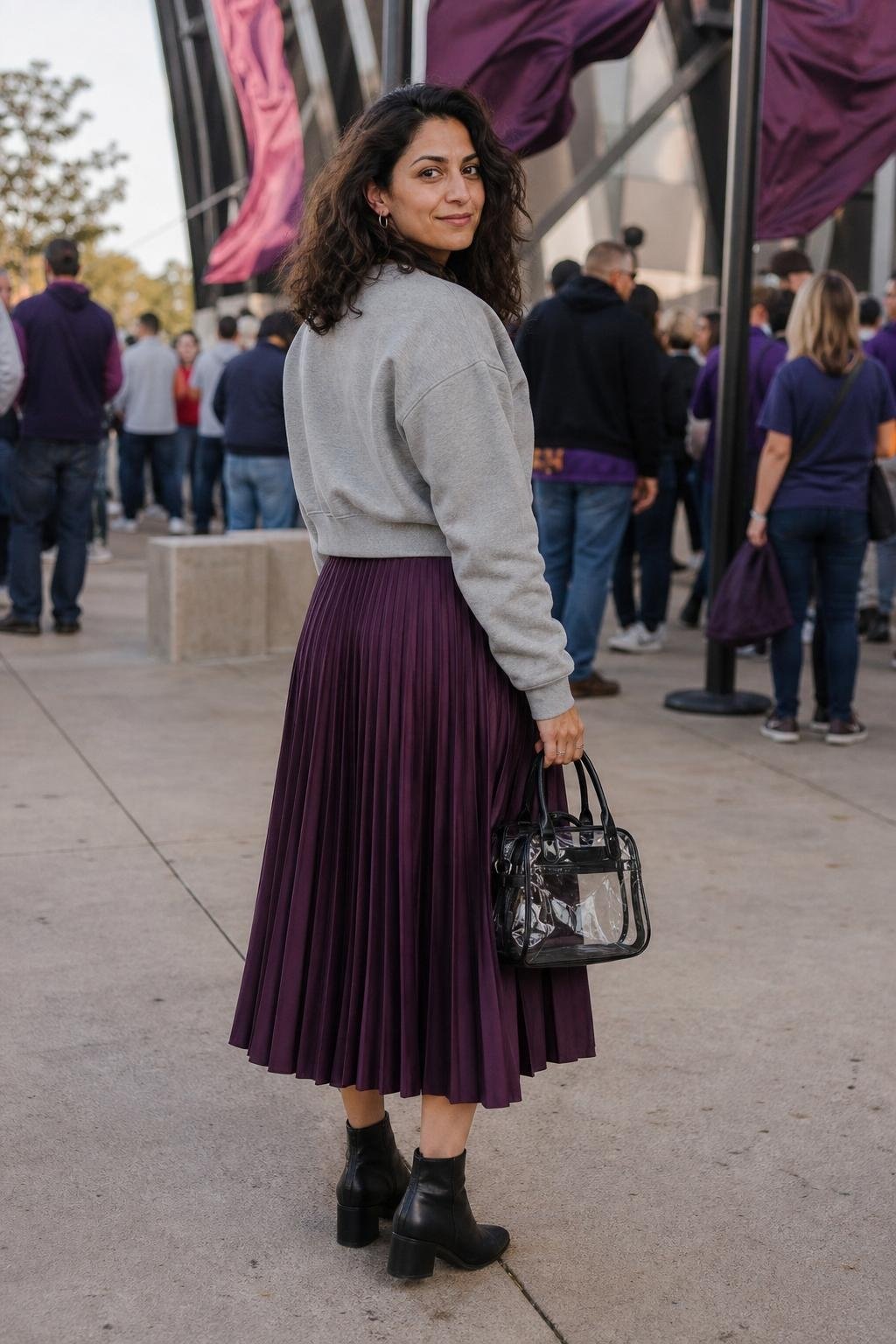 Plum pleated midi skirt, gray team sweatshirt, black ankle boots, stadium plaza with pregame energy (option 1)